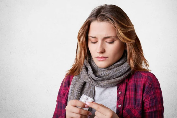 Mujer bonita poco saludable sostiene pastillas, toma medicamentos, trata de bajar la temperatura, cura del frío malo, aislado sobre fondo blanco. Joven linda mujer toma analgésicos o antibióticos, posa en el estudio — Foto de Stock