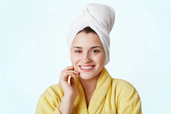 Szervezet ellátás és a wellness fogalma. Nagyon szép, fiatal nő visel a sárga fürdőköpeny és törölköző a fejét, van kellemes mosoly, hogy tartalom után véve zuhanyzóval vagy káddal, elszigetelt fehér háttér felett. — Stock Fotó