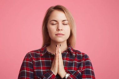 Sadık oldukça kadın modeli palms birlikte basılı tutar, gözlerini kapatır, pembe bir arka plan üzerinde izole hayatında kötü durumu daha iyi ve iyileştirme için büyük umut vardır. Huzurlu ortam.