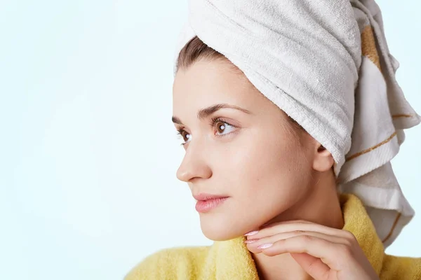 Close up portrait of beautiful young female has healthy pure skin, wears towel and bathrobe, looks thoughtfully aside, going on work, relaxes at home, has hygiene procedures. Body care concept — Stock Photo, Image