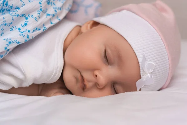 Close up portrait of adorable lovely baby sleeps calmly in bed, covered with warm blanket, has pleasant healthy sweet dream, cared by affectionate parents. Infant care and childhood concept. — Stock Photo, Image