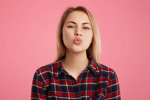 Tiro horizontal de bela fêmea com lábios arredondados, indo para beijar namorado, expressa grande amor e bons sentimentos, isolado sobre fundo rosa. Pessoas, linguagem corporal e expressões faciais — Fotografia de Stock