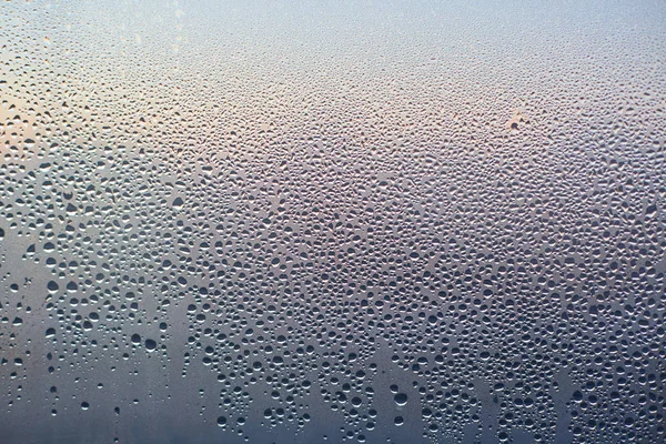 Rain drops on glass background. Pattern of water drops after heavy rain, View from indoor. Abstract wet texture. Transparent drops of different shapes