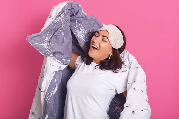 Närbild porträtt av gäspande kvinna bär filt och sovmask, håller ögonbindel på pannan och hålla ögonen stängda, vinkig kvinna poserar isolerad över rosa bakgrund. Begreppet sömnstörningar. — Stockfoto
