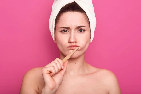 Close up portret atrakcyjnej białej kobiety z ciemnymi włosami pozowanie izolowane na różowym tle, femaklw z gołymi ramionami i białym ręcznikiem na głowie, pani patrząc w aparat, mycie zębów. — Zdjęcie stockowe