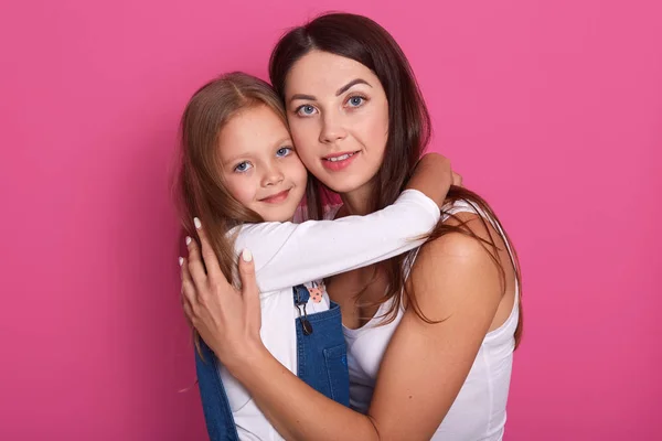 Woman wearing casualo clothes have fun with cute child baby girl. Mommy and her little kid daughter posing isolated over pink background, studio portrait. Family, parenthood and childhood concept — Stock Photo, Image
