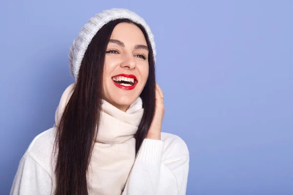 Mujer caucásica relajada con suéter blanco cálido, de pie y riendo en el estudio. Chica increíble con maquillaje brillante expresando felicidad, espacio de copia para su anuncio o texto promocional . —  Fotos de Stock