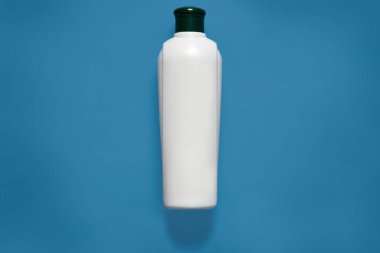 Kozmetik paket, maket, siyah kapaklı beyaz plastik şişe, temiz plastik kap, promosyon metni veya reklam için kopya alanı, mavi stüdyo arka planında izole edilmiş..