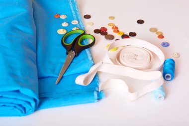 Yatay iş yeri, kumaş, makas, mezura, düğme ve beyaz arka planda izole edilmiş terzi ekipmanları. Moda, giyim endüstrisi, kıyafet yapma konsepti..