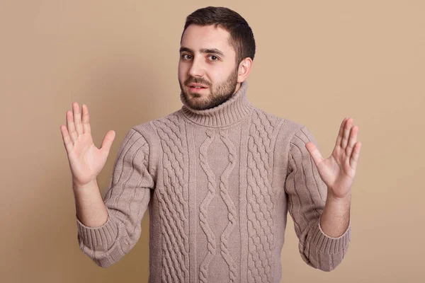 Horizontal shot of young happy crazy man showing big size gesture with hands, emphasizing great amount of something, bearded guy wearing warm knitted sweater, looking at camera. Body language concept. — Stock Photo, Image