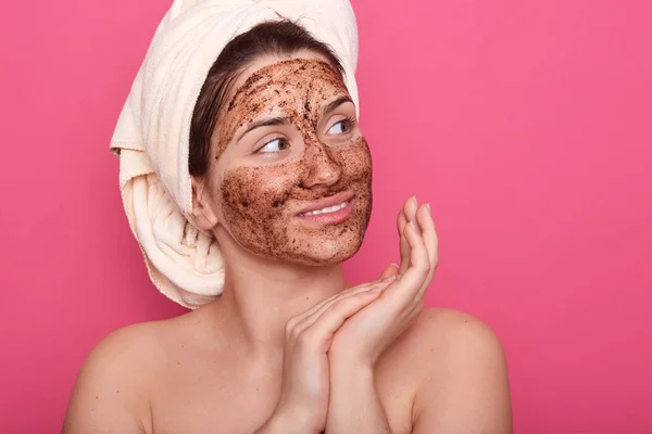 Tutup potret gadis dibungkus rambut dengan handuk, berpose dengan kulit ditutupi oleh topeng. Model dengan wajah cokelat, melakukan prosedur pagi, melihat ke samping, berdiri dengan telanjang seharusnya rumah . — Stok Foto