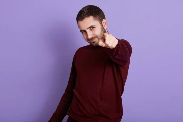 Εικόνα ενός χαρισματικού νεαρού άνδρα να κάνει χειρονομία, να δείχνει τον δείκτη του στην κάμερα, να σηκώνει το χέρι, να φοράει σκούρο κόκκινο φούτερ, να είναι ικανοποιημένος, να στέκεται απομονωμένος πάνω από λιλά φόντο. — Φωτογραφία Αρχείου