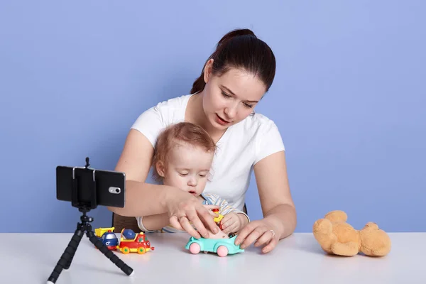 Image of beautiful young mother playing with her little son, mommy and infant play with toy car and filming video for her vlog, mum making content for her vlog about childre. Technology concept. — Stock Photo, Image