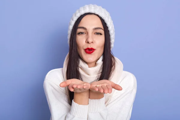 Close up portrait of charismatic lovely sweet brunette putting hands together, sending kiss, having peaceful facial expression, being in good mood, looking directly at camera, having red lips. — Stockfoto