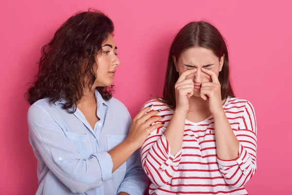 Potret seorang gadis remaja menghibur gadis lain setelah putus, perempuan mengenakan kemeja bergaris menangis di studio, temannya datang ke bawah, mengenakan pakaian kasual. Konsep persahabatan. . — Stok Foto