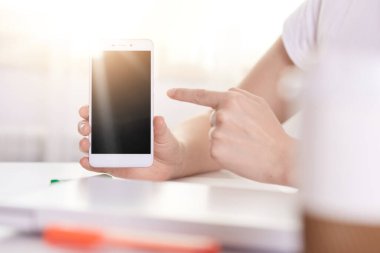 Bilinmeyen bir kadının cep telefonu tutarken çekilmiş resmi, boş siyah ekranlı bir cihaz, yüzsüz bir kadın işaret parmağıyla cihazı işaret ediyor. Reklam veya tanıtım için alanı kopyala.