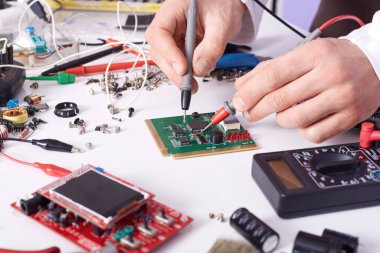 Kimliği belirsiz teknisyen laboratuvarda akıllı telefonun ana kartını onarıyor, radyocu da bilgisayarın yedek parçasını lehimliyor. Bilgisayar donanımı, cep telefonu, elektronik, onarım, güncelleme ve teknoloji kavramı.