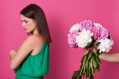 Yüzsüz adamın portresi, pembe ve beyaz şakayık çiçekleri erkek arkadaşına ters poz veren, pembe stüdyo arka planında izole edilmiş rahatsız bir mankene sunuyor..