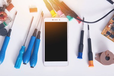 Reklam ya da promosyon için siyah ekranlı modern akıllı telefonun resmi. Beyaz yüzeyde, tornavidaların yanında elektronik akıllı telefon teknolojisi servisinde arızalı cep telefonu..