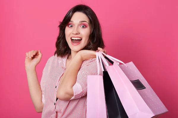 빛나는 여자의 행복해 보이는 웃으며 쇼핑백을 분홍색 스튜디오 고립된 벌리고 — 스톡 사진