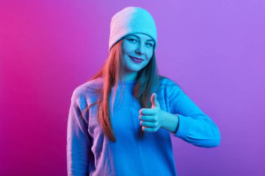 Şapka ve kazak giyen, el kaldıran, el hareketi yapan, kameraya doğrudan bakan, hoş bir yüz ifadesine sahip, onaylayan,.