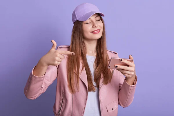 여성이 드레스를 모자를 핸드폰을 비디오를 게임기 화면을 가리키며 스튜디오의 라일락 — 스톡 사진
