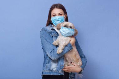 Tıbbi korumalı yüz maskesi takan yetişkin bir kadının yatay görüntüsü. Elinde maske olan bir kadın. Yeşil arka planda izole edilmiş. Coronavirus, covid 19, hastalık, salgın konsepti.