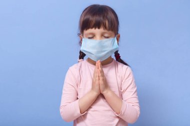 Coronavirus ve Hava Kirliliği PM2.5 kavramı. PM2.5 'u korumak için maske takan küçük Çinli kız Corona virüsünün salgınını durdurmak için dua ediyor. Wuhan Coronavirüs ve salgın virüs belirtileri..