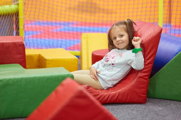 stock image Indoor picture of relaxed joyful little child looking directly at camera, lying at playground, chilling out alone, being delighted with weekend time, having fun, wearing casual clothes. Child concept.