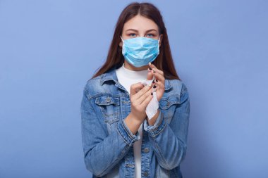 Mavi arka planda izole edilmiş, ellerini antibakteriyel dokularla silerken, mikropları öldürürken, güvenlik önlemlerini alırken, maske takarken çekilmiş kapalı çekimler. Coronavirus konsepti.