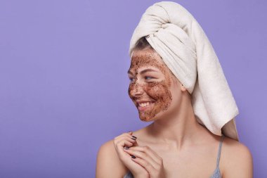 Çekici, çekici, genç bir bayanın güzel bir yüz ifadesine sahip, kafasında beyaz bir havluyla, iyi bir ruh halinde, maske taktığı görüntüsü. Reklam için eşdeğer alan.