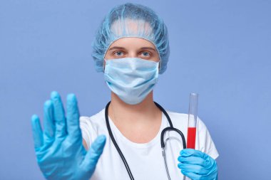 Coronavirus testi için kanla tüp tutan, el kaldıran, koruyucu maske takan, şapka ve eldiven takan ciddi bir doktorun resmi. Kontrol durumu. Covid19 konsepti.