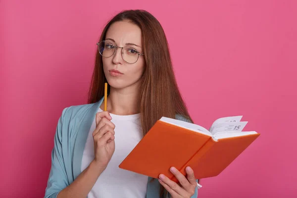 Εικόνα Σκεπτόμενης Έξυπνης Γυναίκας Που Φοράει Γυαλιά Κρατάει Πορτοκαλί Σημειωματάριο — Φωτογραφία Αρχείου