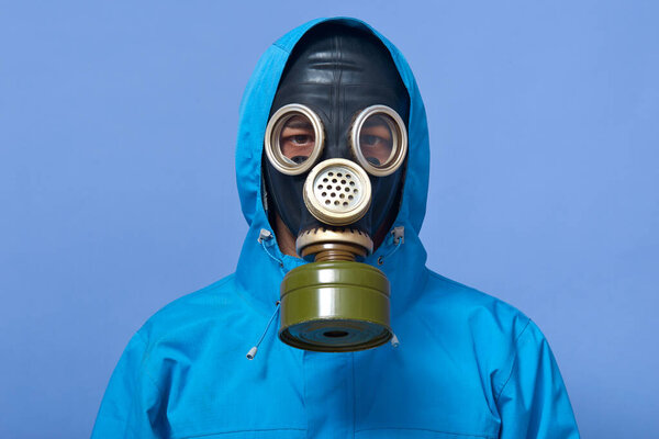 Image of ecologist wearing gas mask frights with pouring dangerous chemicals to ground, world industry pollutes atmosphere with tons of dust and other harmful things. Ecological problems concept.