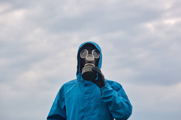 Closeup portrait of chemical scientist or ecologist posing outdoor, dresses blue uniform and respirator, scientist explores surroundings, calls on to protect our environmental. Ecology concept.