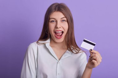 Mıknatıslı arka planda izole edilmiş, ağzı geniş, neşeli bir yüz ifadesi olan, kredi kartı tutan güzel bir kadının yakın portresi. Kadınlar ve gider kavramı.