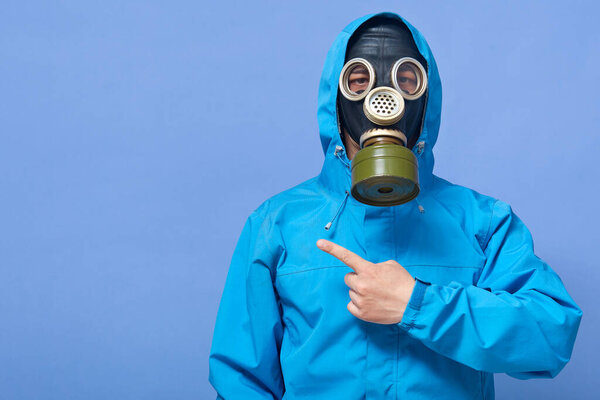 Image of liquidating agent looking directly at camera, making gesture, showing direction with forefinger, being in gas mask and uniform, protecting himself from poison. Copyspace for advertisement.