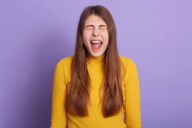 Uzun saçlı, gözlerini kapalı, mutlu bir şekilde bağıran, günlük kıyafetler giyen, olumlu duygular besleyen, mutluluğu ifade eden bir kadının yatay görüntüsü. Bayanın harika haberleri var. İnsanların duyguları.