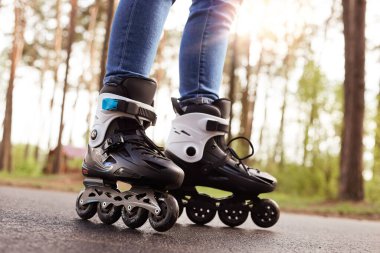 Patenlerin yakın plan fotoğrafı, zamanını geçirmek için paten giyen bilinmeyen biri, temiz havada yolda tekerlekleri olan siyah patenler, yeni bir şeyler almaya çalışan. Paten konsepti.