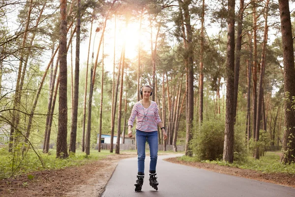 Horizontaal Beeld Van Vrolijke Tedere Aantrekkelijke Jonge Vrouw Die Rolschaatst — Stockfoto