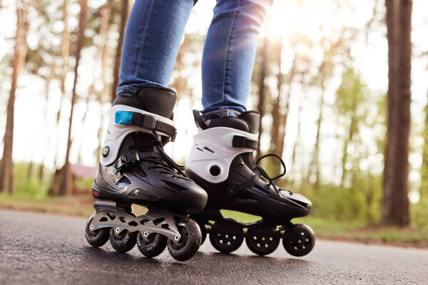 Крупный план роликов, неизвестный в роликовых коньках для активного времяпровождения, черные ролики с колесами на свежем воздухе, примерка новой покупки. Концепция роликового катания
.
