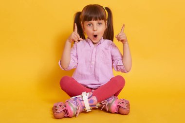 Duygusal olarak karizmatik, at kuyruklu, ağzı geniş olan, parmaklarını kaldıran, jest yapan, fikir sahibi olan, kameraya doğrudan bakan, bacak bacak bacak üstüne atan, tekerlekli patenlere sahip bir çocuk..