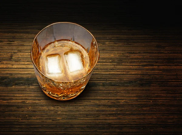 Perfecto vaso de whisky y hielo sobre fondo de madera texturizada —  Fotos de Stock