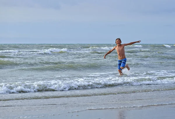 Giovane ragazzo giocare in onde — Foto Stock