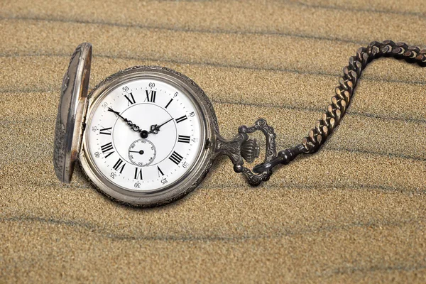 Антикварные карманные часы на песке — стоковое фото