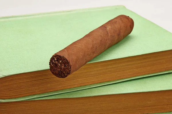 Kubanische braune Zigarre posiert auf einem Stapel alter Bücher — Stockfoto