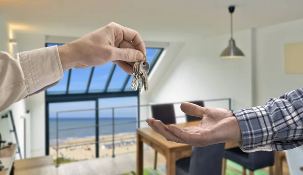 Ріелтор дає ключ від будинку покупцеві в сучасній вітальні — стокове фото