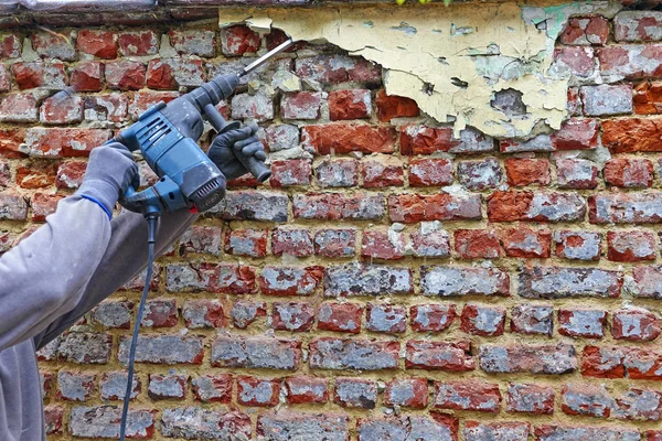 Arbeider med elektrisk hammer, rengjør rød murvegg – stockfoto