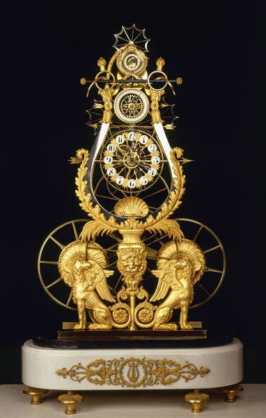 Antique clock with Griffin and wheels figurines on black — Stock Photo, Image