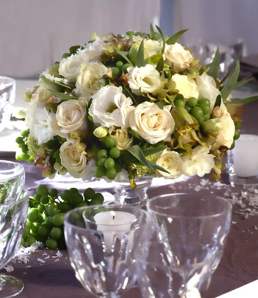 Fiori con rose al centro di un tavolo da pranzo festivo — Foto Stock